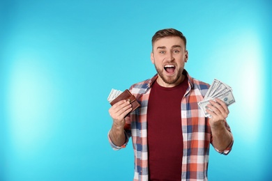 Portrait of emotional young man with money on color background. Space for text