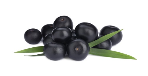 Pile of fresh ripe acai berries and green leaves on white background