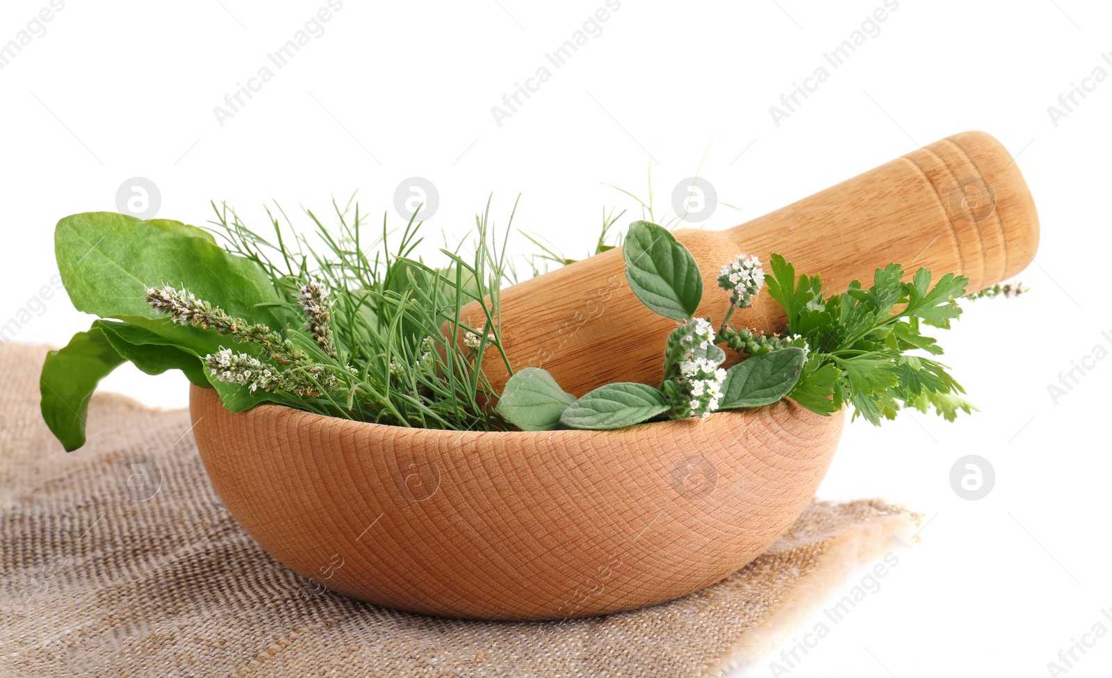 Photo of Wooden mortar, pestle and different herbs on cloth against white background