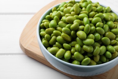 Photo of Bowl of delicious edamame beans on white wooden table, closeup