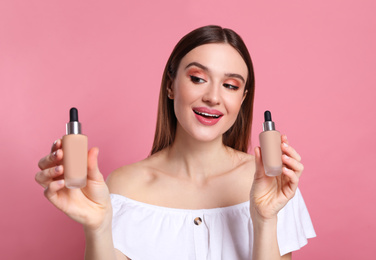 Beauty blogger showing bottles of foundation on pink background