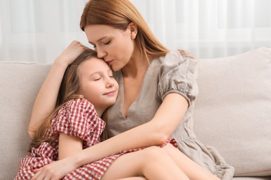 Photo of Mother and her cute daughter on sofa at home