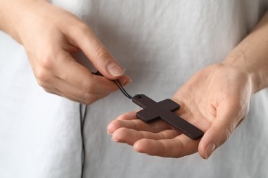 Photo of Woman holding wooden Christian cross, closeup view