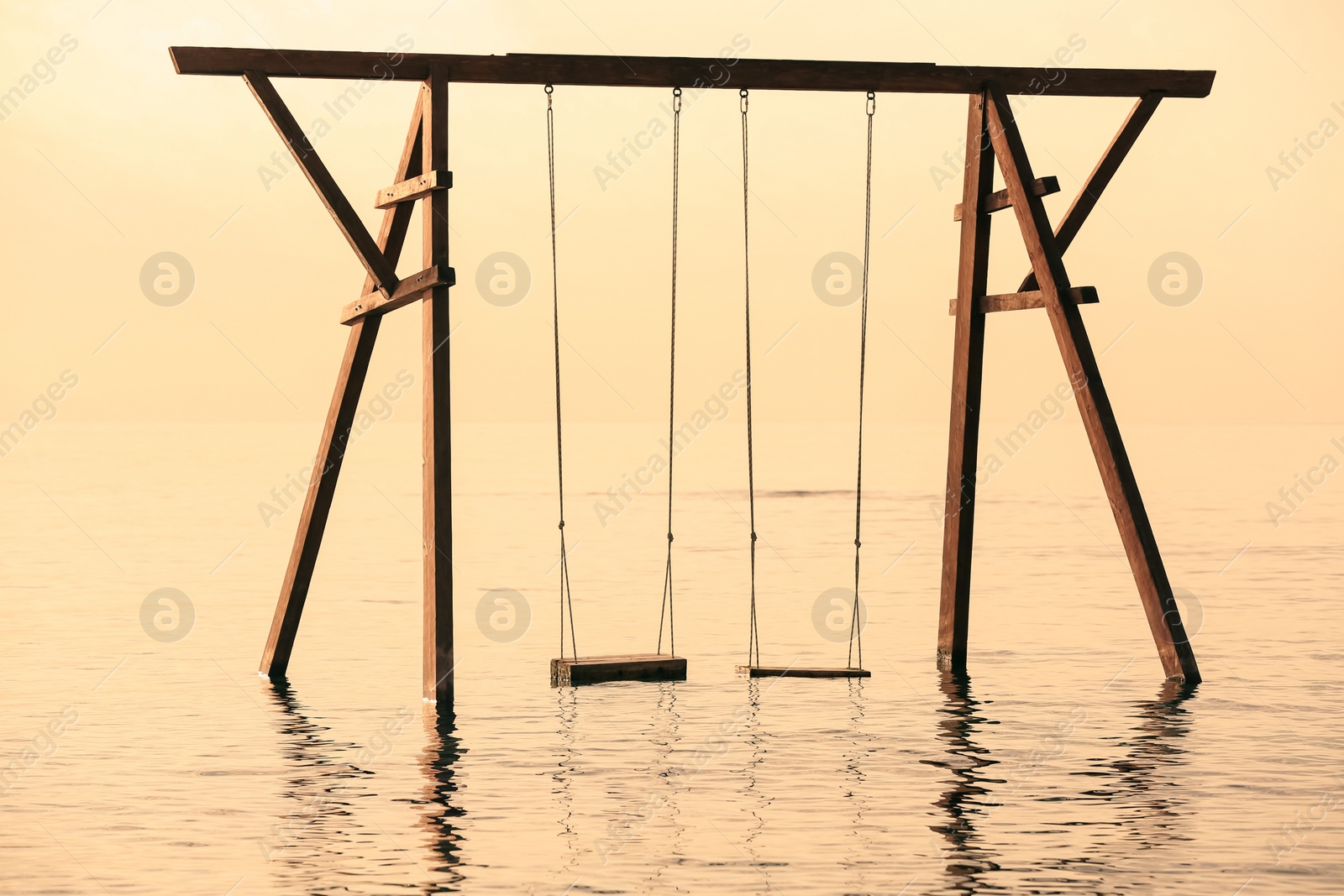 Photo of Picturesque view of swing in water on sunrise