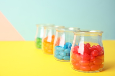 Photo of Jars of colorful jelly beans on table. Space for text