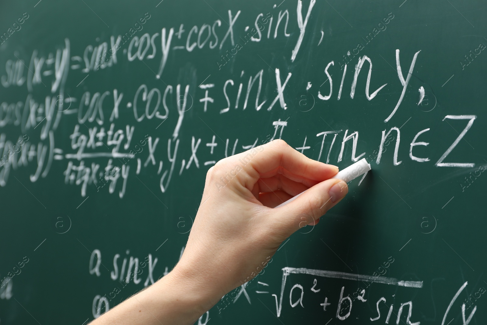 Photo of Teacher writing down math equation on green board, closeup
