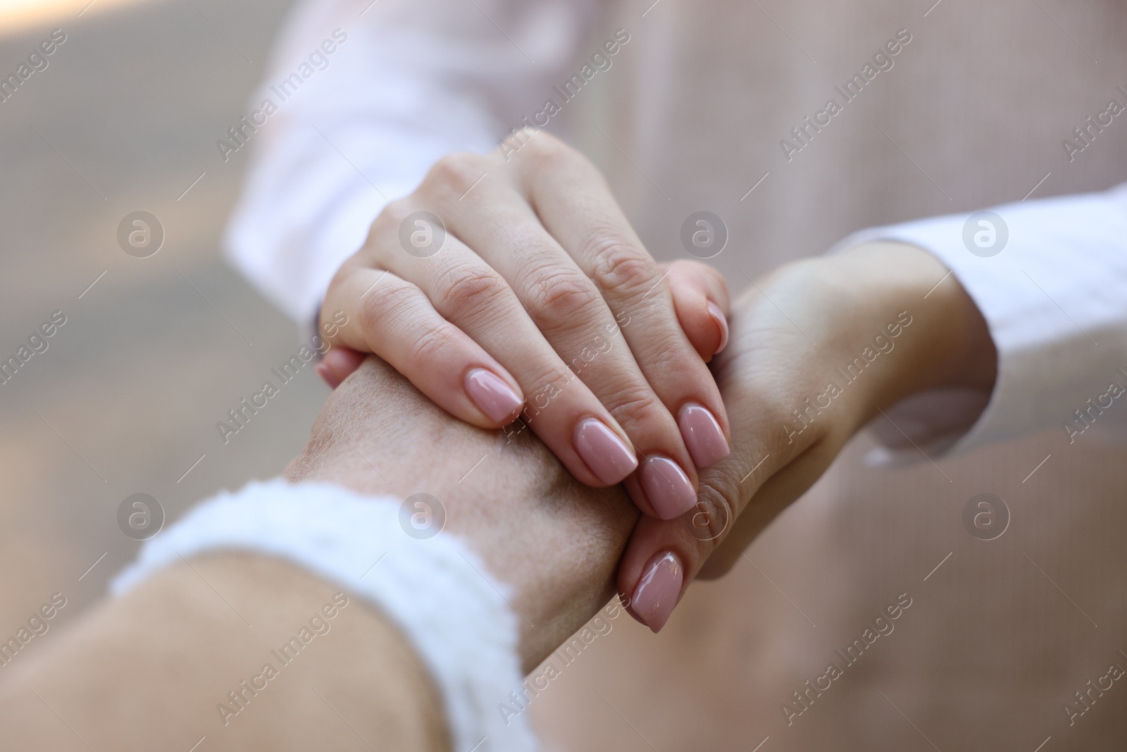 Photo of Trust and support. Women joining hands on blurred background, closeup