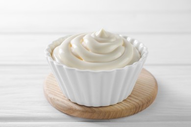 Fresh mayonnaise sauce in bowl on white wooden table, closeup