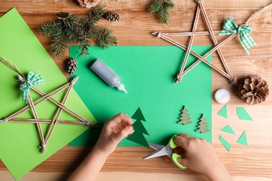 Little child making Christmas card at wooden table, top view