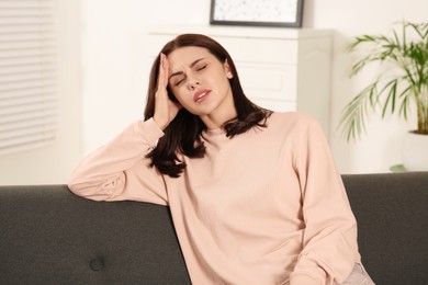 Young woman suffering from headache indoors. Hormonal disorders