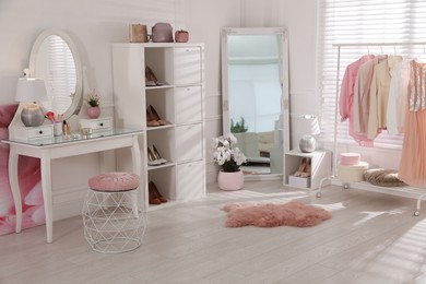 Stylish dressing room interior with shelving unit, table and mirror