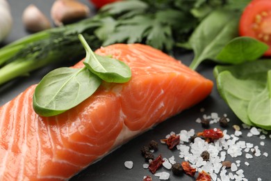 Photo of Fresh salmon and ingredients for marinade on black table, closeup