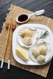 Photo of Raw scallops with green onion, rosemary, lemon and soy sauce on dark textured table, top view