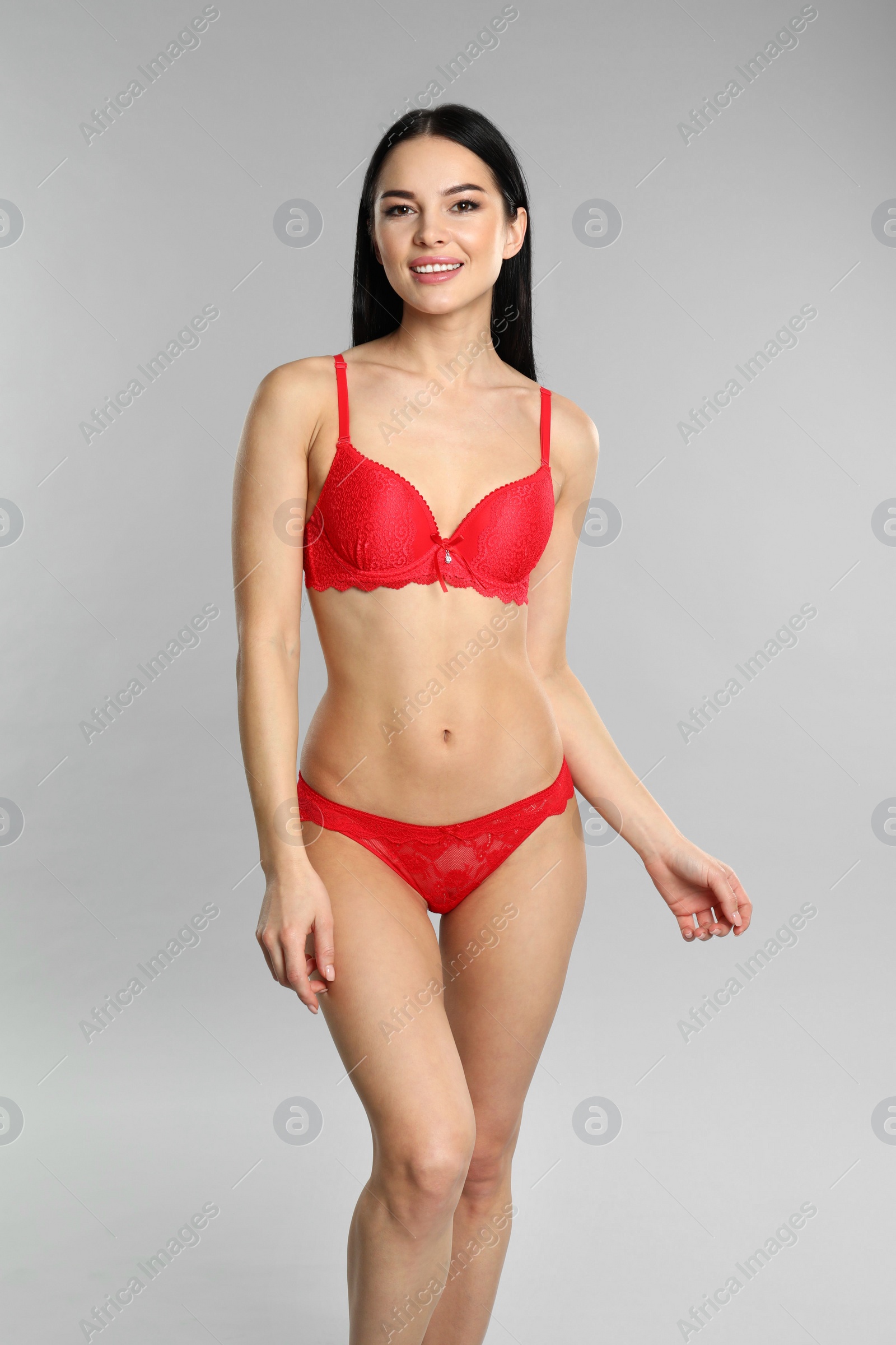 Photo of Beautiful young woman in red underwear on grey background