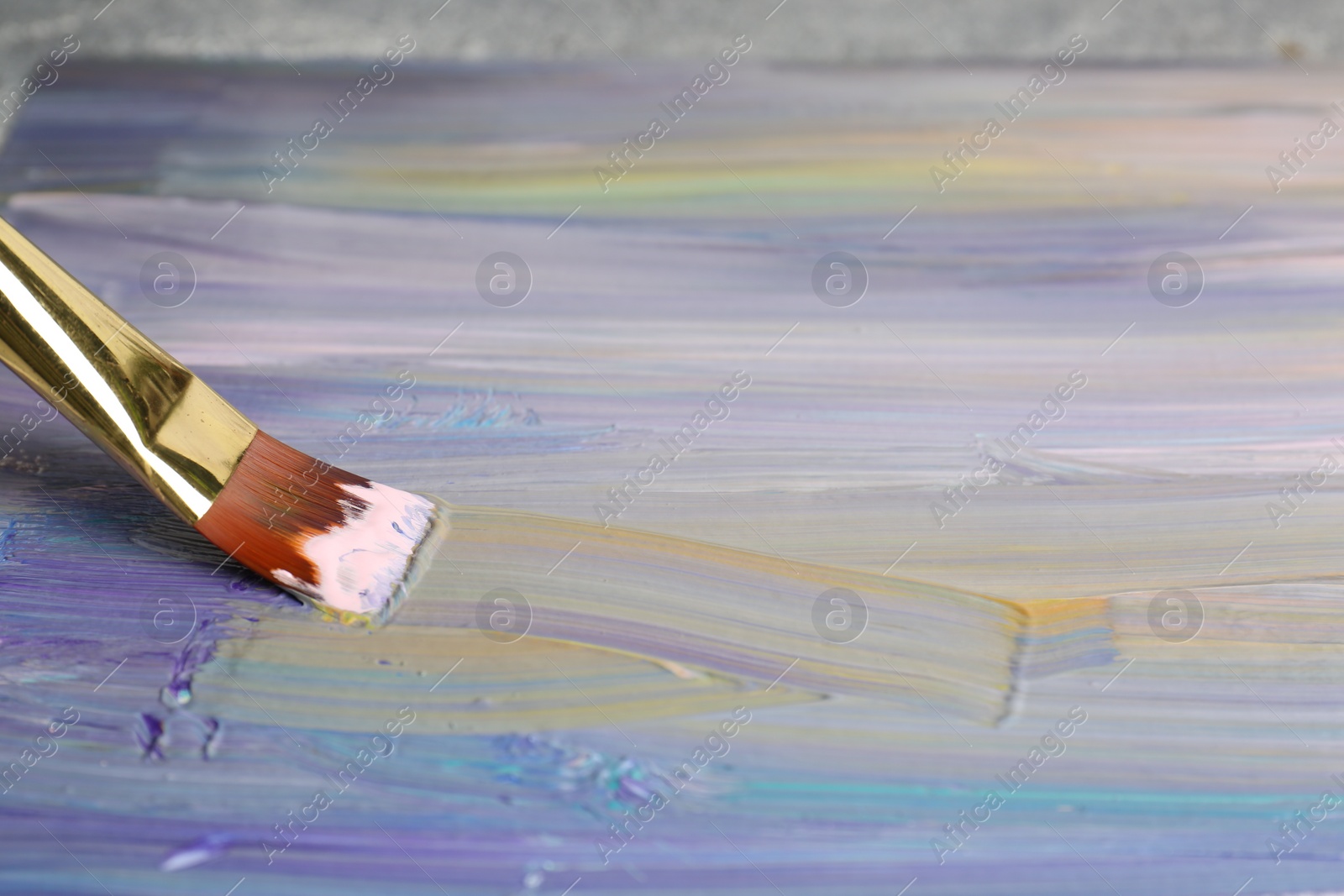 Photo of Strokes of colorful paints and brush on canvas, closeup