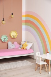Cute child's room interior with beautiful rainbow painted on wall