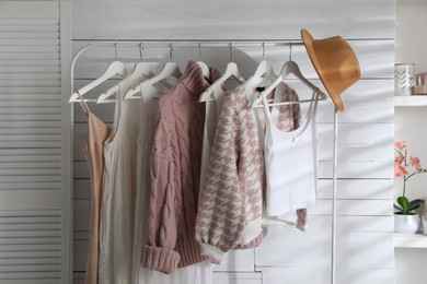 Photo of Rack with different stylish clothes, hat and decorative elements in dressing room