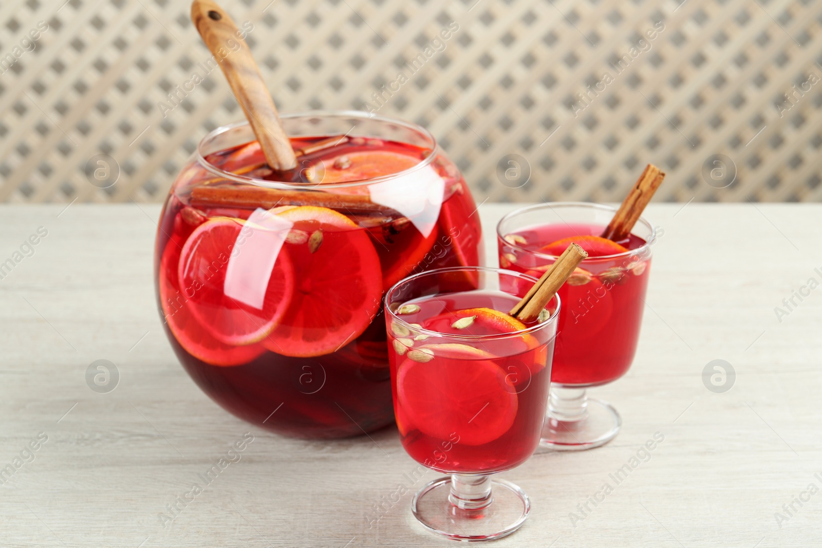 Photo of Glasses and bowl with aromatic punch drink on white wooden table