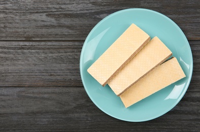 Photo of Plate with delicious crispy wafers on wooden table, top view. Space for text