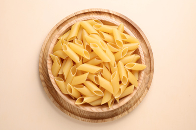 Photo of Pennoni pasta on beige background, top view