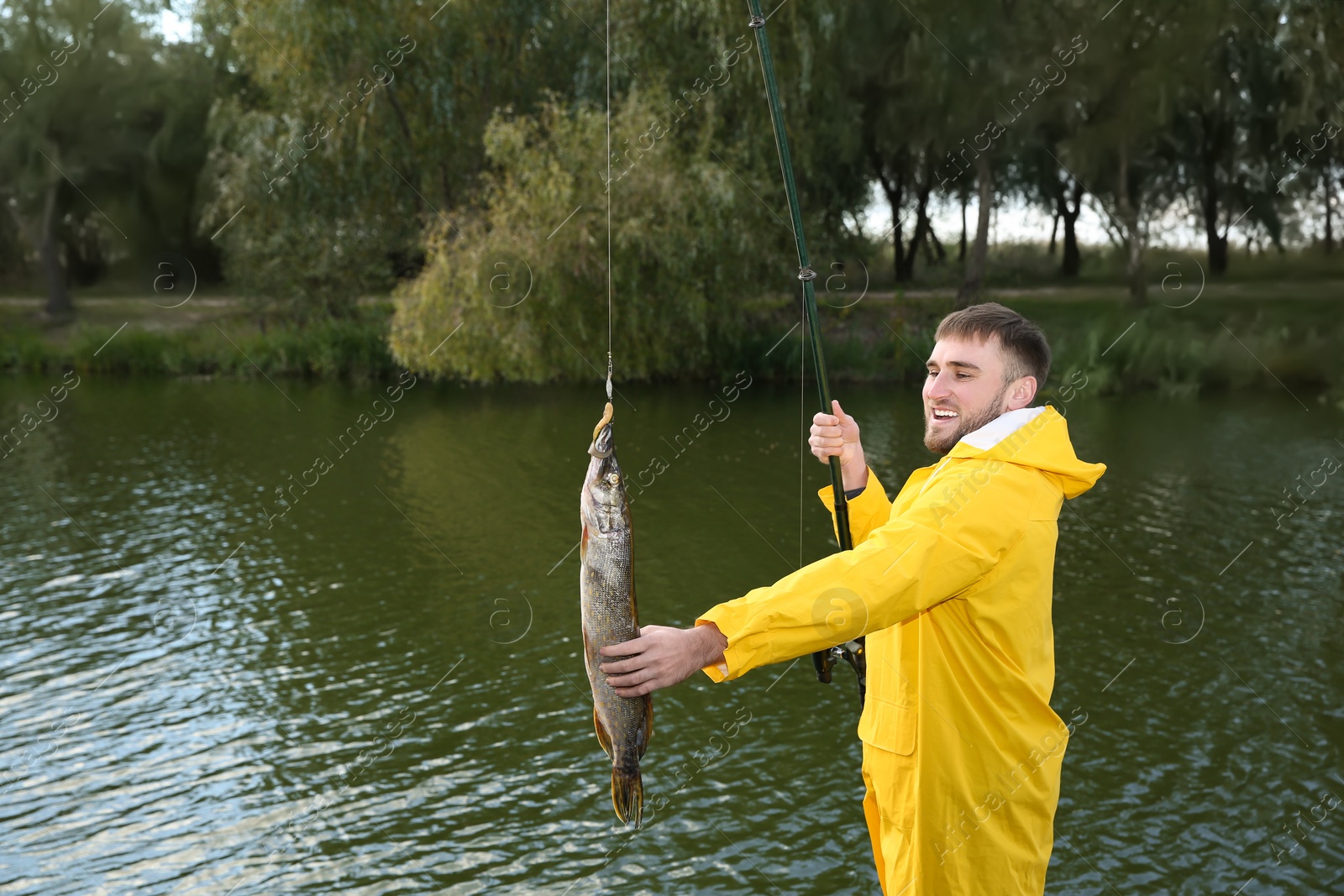 Photo of Man with rod and catch fishing at riverside. Recreational activity