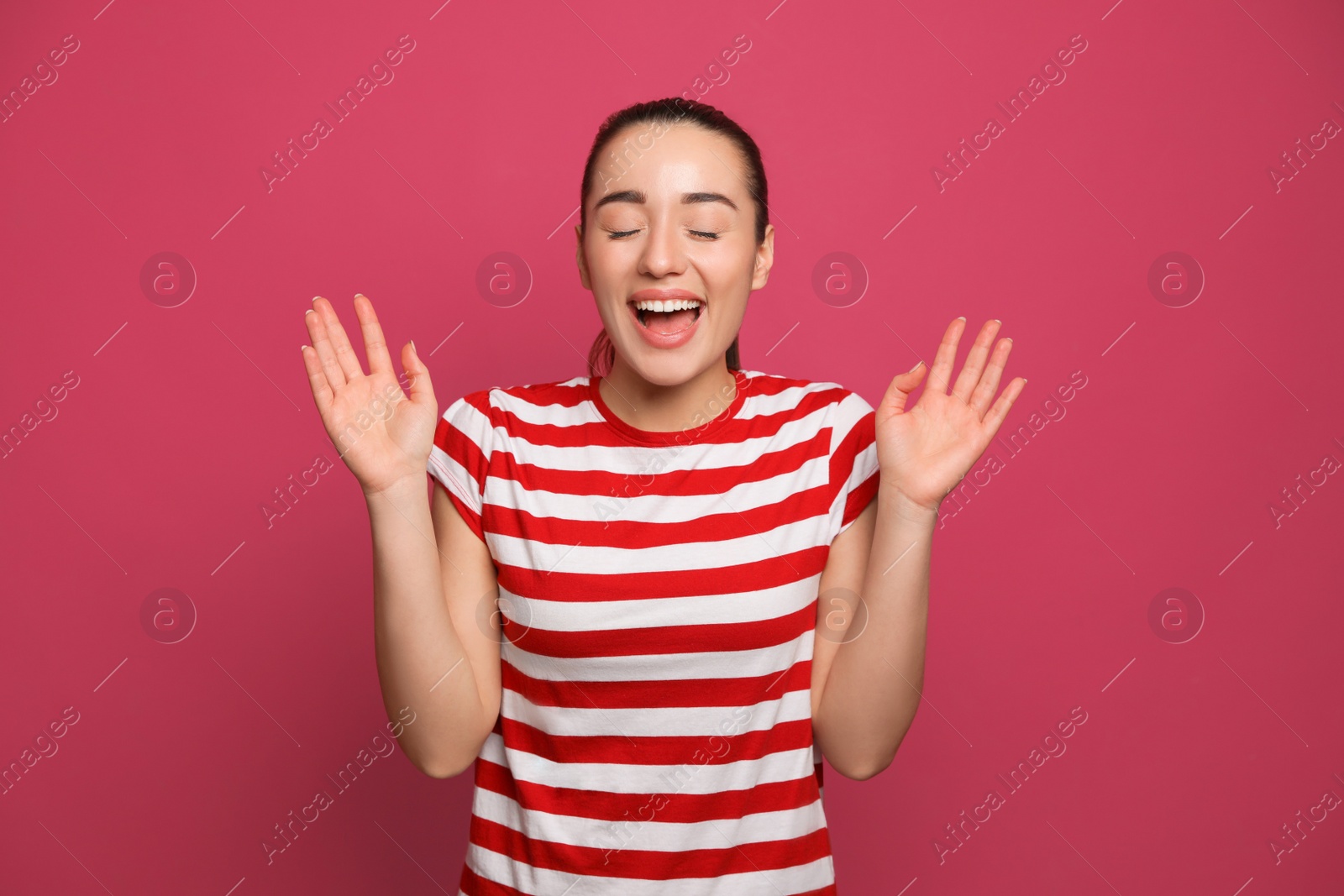 Photo of Beautiful young woman laughing on maroon background. Funny joke