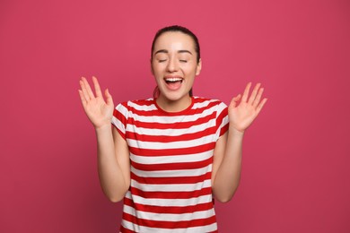 Beautiful young woman laughing on maroon background. Funny joke