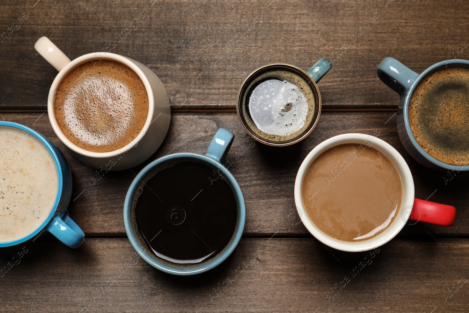 Photo of Cups of fresh aromatic coffee on wooden table, flat lay