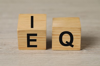 Wooden cubes with letters E, I and Q on table