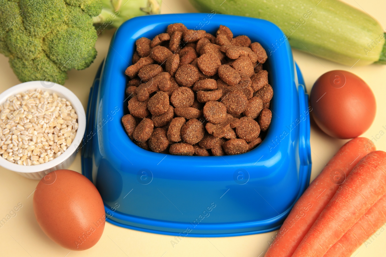 Photo of Dry pet food and products on beige background, closeup