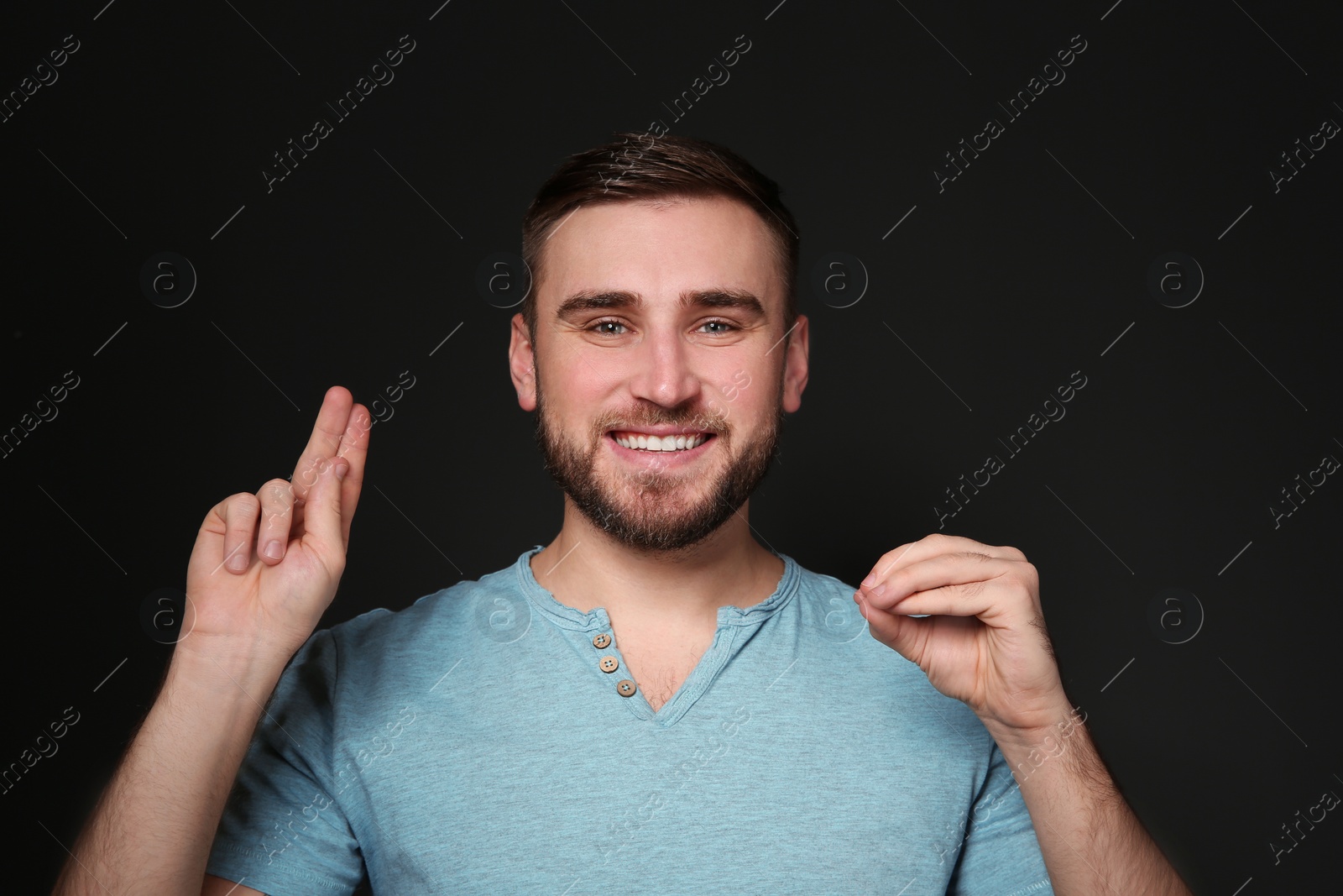 Photo of Man using sign language on black background