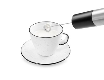 Whisking milk in cup with mini mixer (frother wand) isolated on white