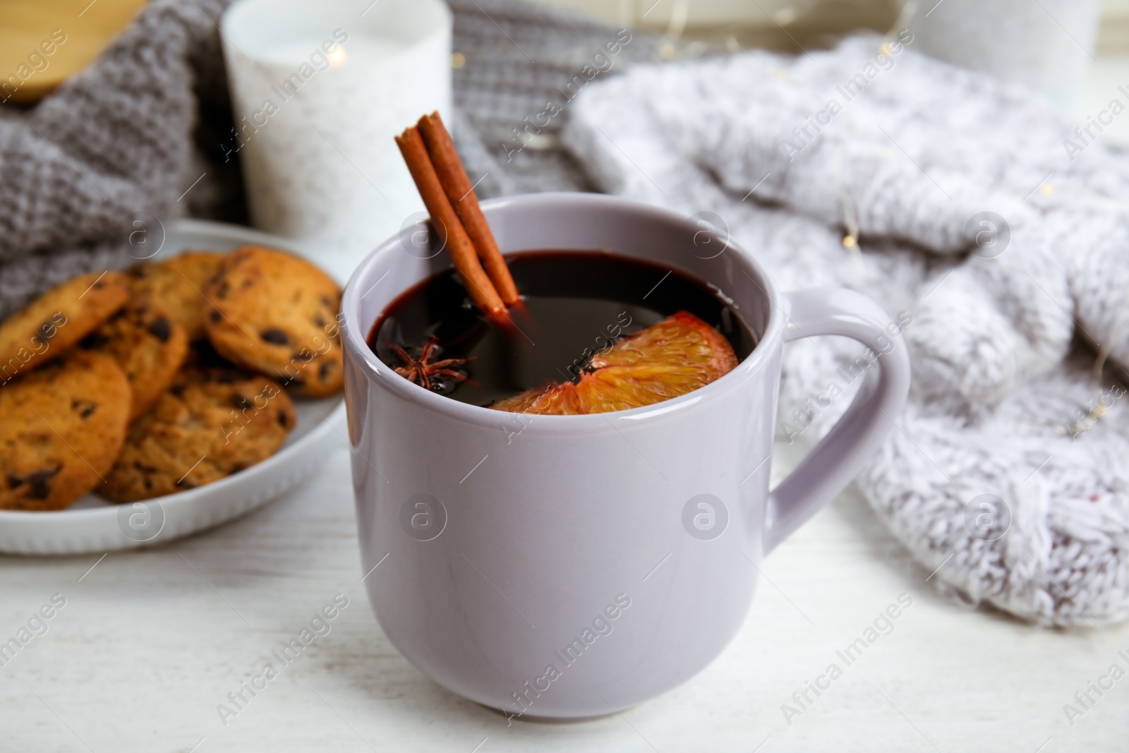 Photo of Cup of hot mulled wine on white wooden table. Winter drink