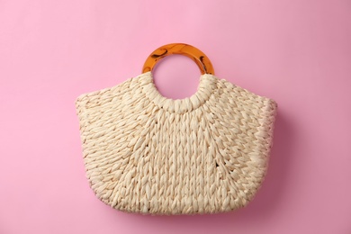 Photo of Elegant woman's straw bag on pink background, top view