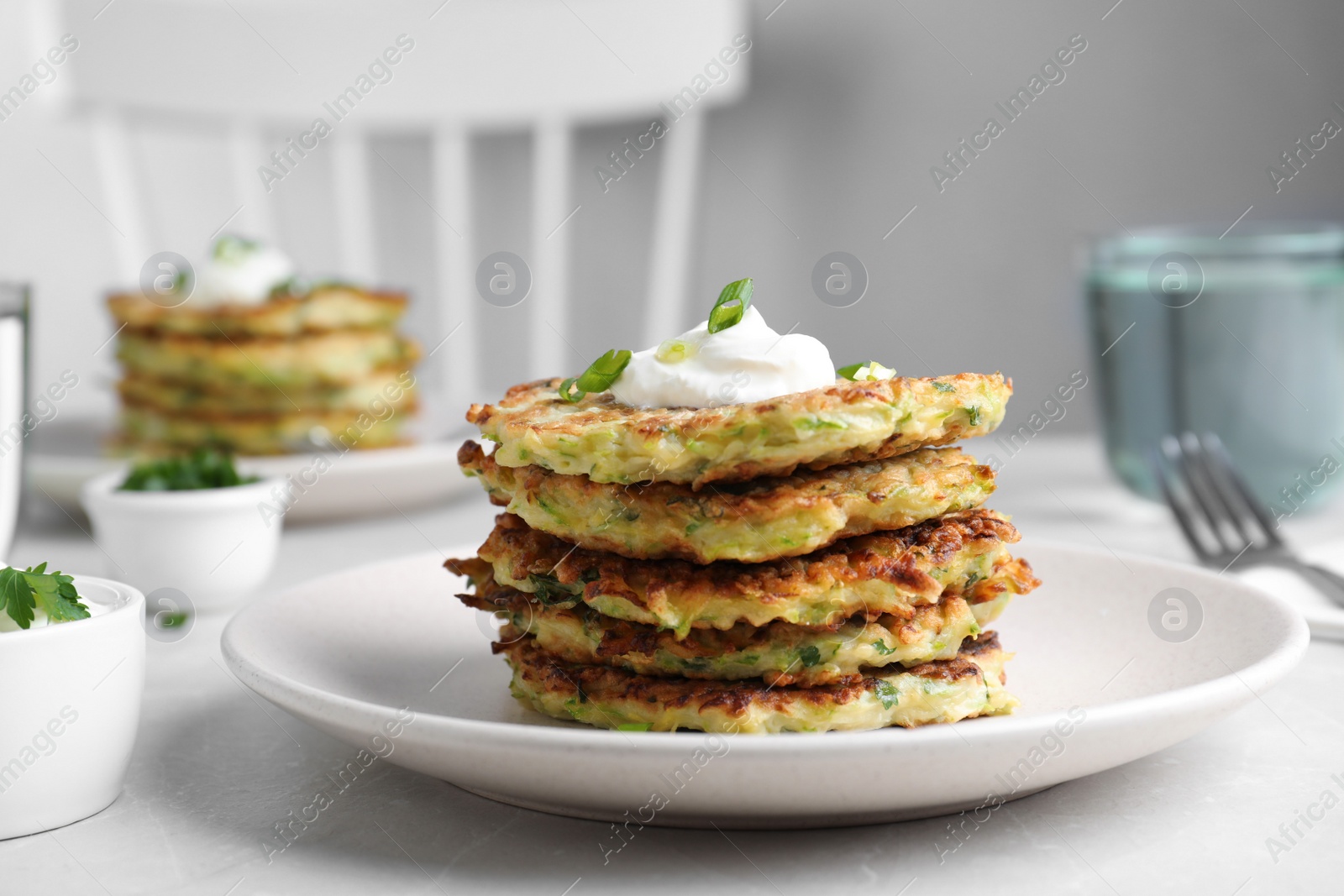 Photo of Delicious zucchini fritters served on light table indoors, closeup
