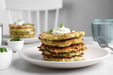 Photo of Delicious zucchini fritters served on light table indoors, closeup