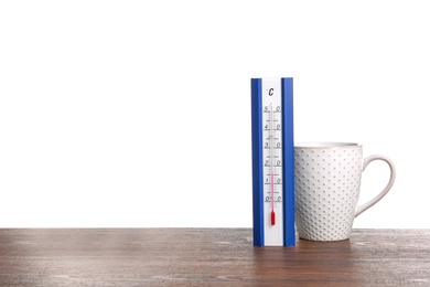 Photo of Thermometer and cup of hot tea on wooden table against white background. Space for text