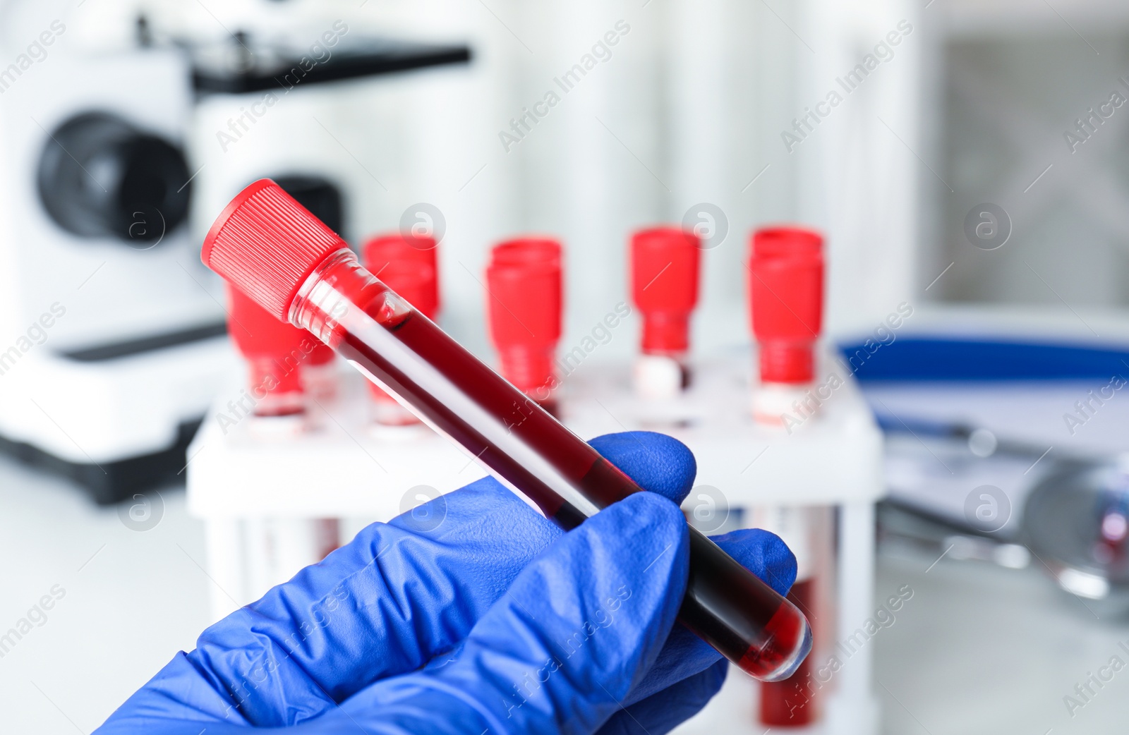 Photo of Scientist holding test tube with blood sample at table, closeup. Virus research