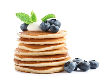 Tasty pancakes with blueberries, sauce and mint on white background