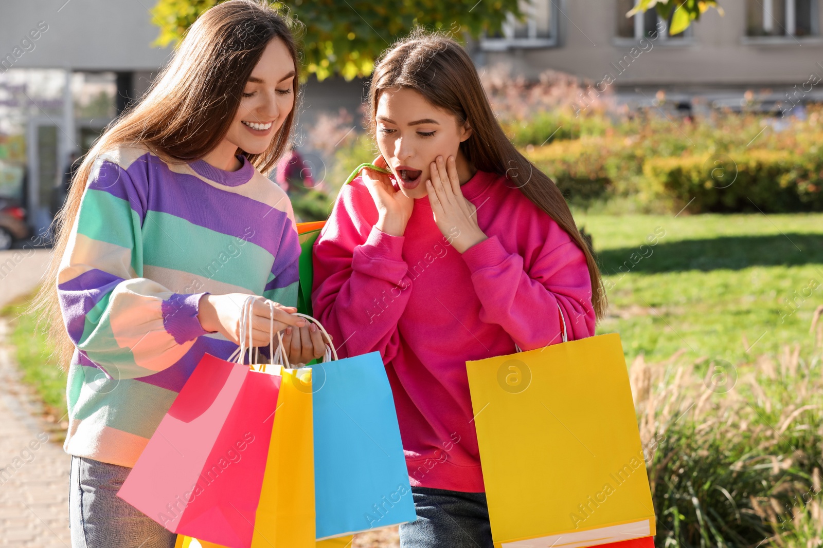 Photo of Beautiful young women with shopping bags on city street