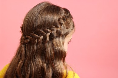 Photo of Little girl with braided hair on pink background, back view. Space for text