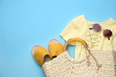 Flat lay composition with woman's straw bag on light blue background. Space for text