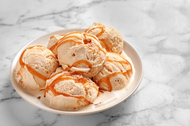 Photo of Tasty ice cream with caramel sauce on plate