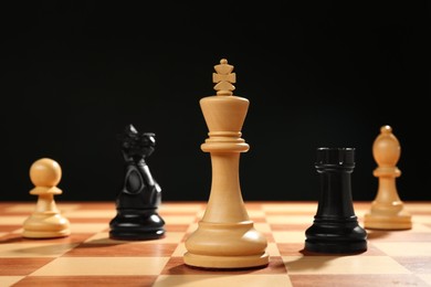 Photo of Different game pieces on chessboard against dark background