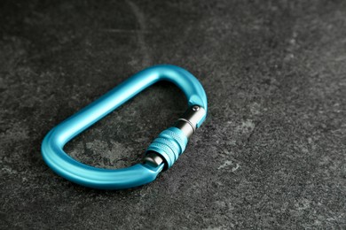 Photo of One metal carabiner on black table. Space for text