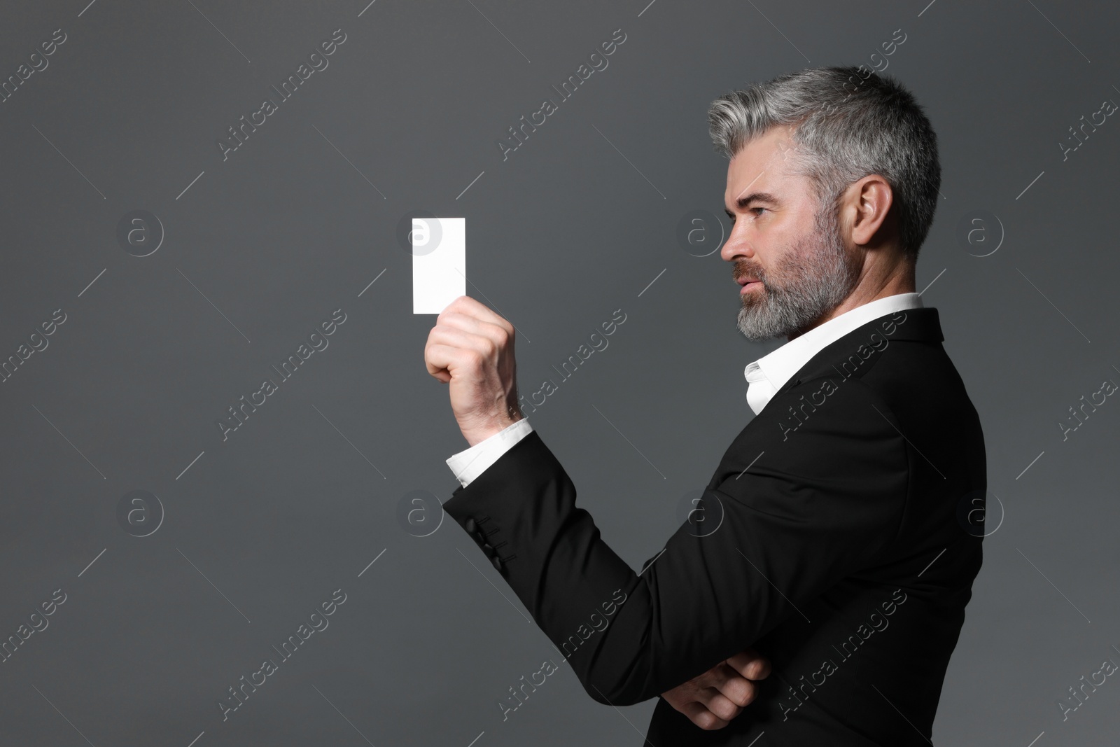 Photo of Handsome businessman holding blank business card on grey background. Space for text