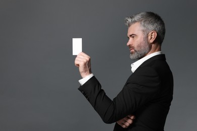 Photo of Handsome businessman holding blank business card on grey background. Space for text