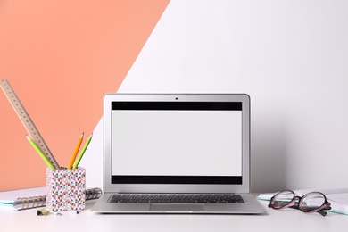 Modern laptop and stationery on table in office