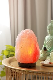 Photo of Himalayan salt lamp, buddha figure and crystals on golden table indoors, space for text