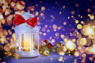 Image of Christmas lantern with burning candle and festive decor on table. Magical atmosphere